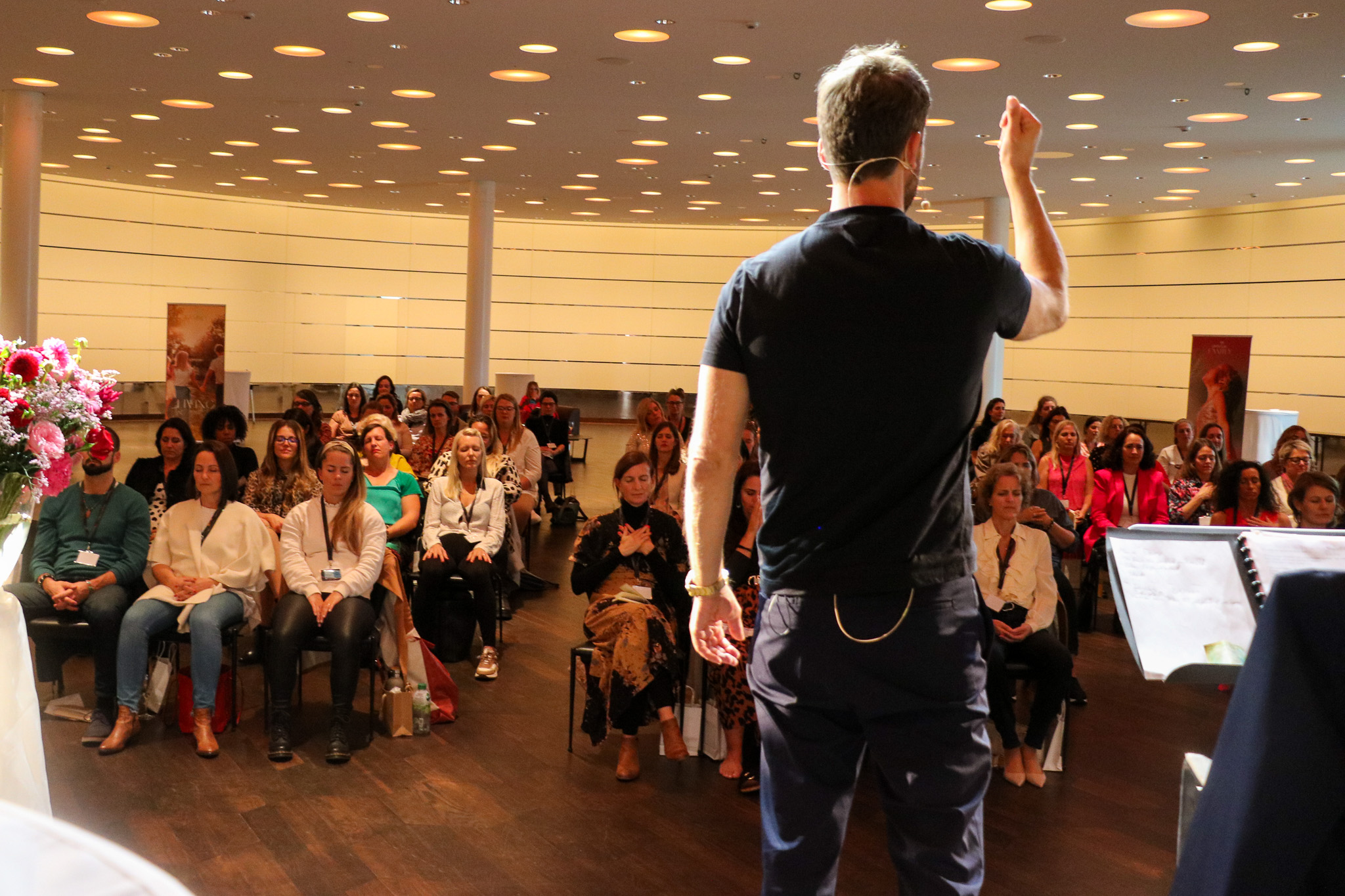 Speaker guiding a seated audience through a meditation