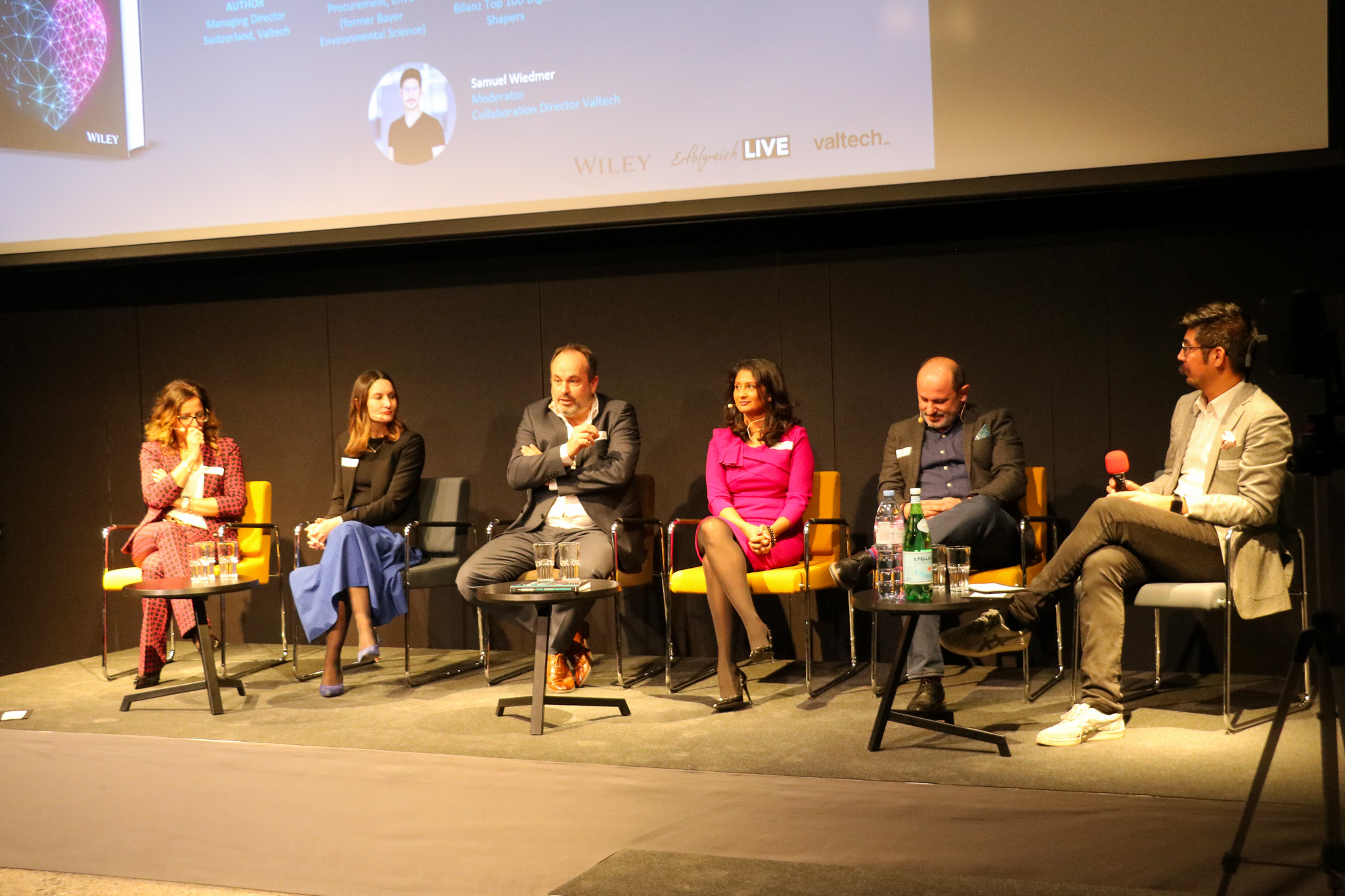 Six panellists in conversation on stage